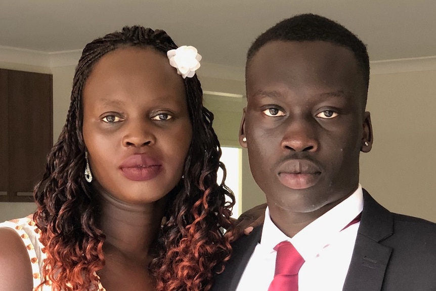 Aguer Lual Akec stands beside his mother, dressed for a formal event.