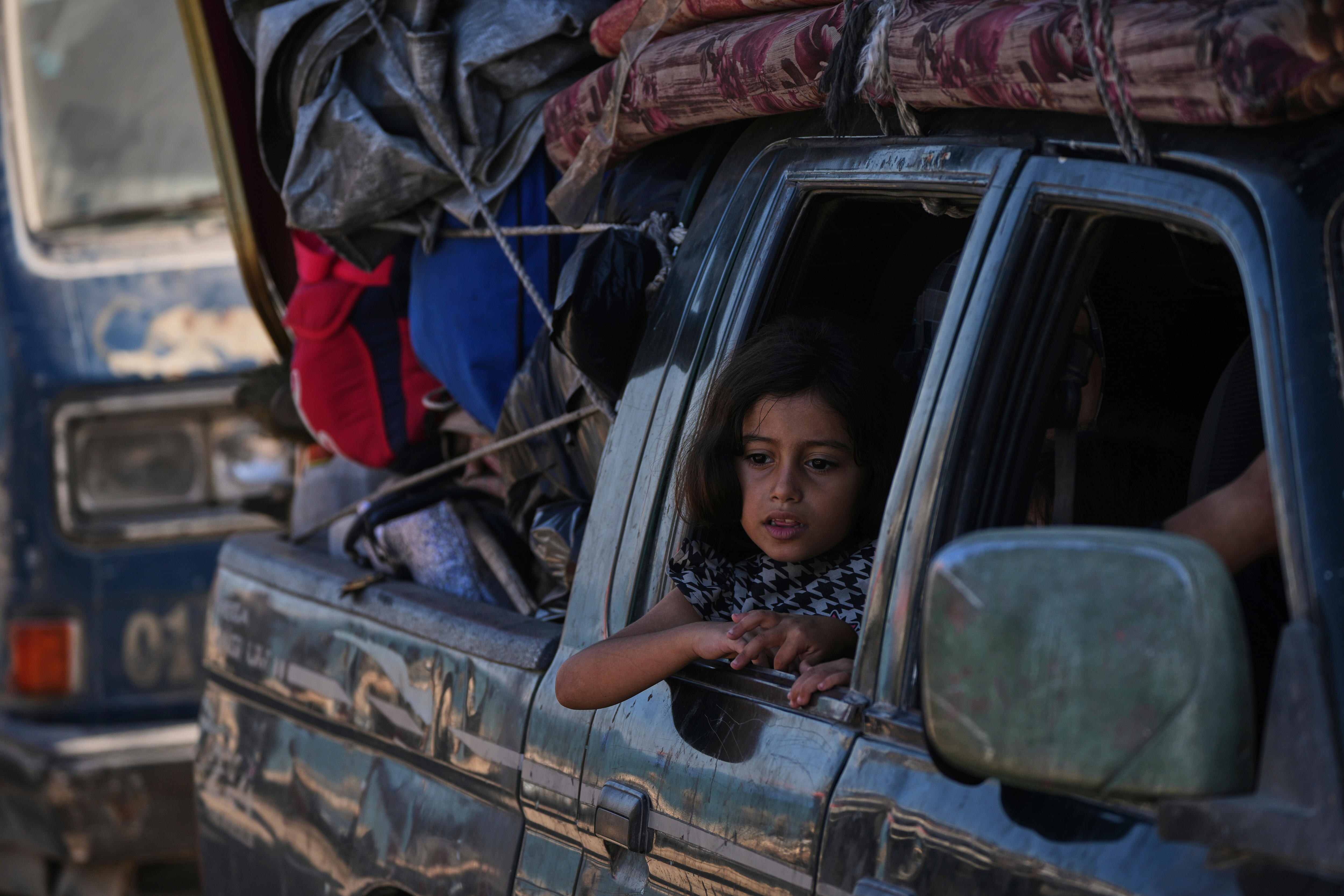 A young girl leans out the back window of a ute laden with possessions as it drives out of Gaza City.
