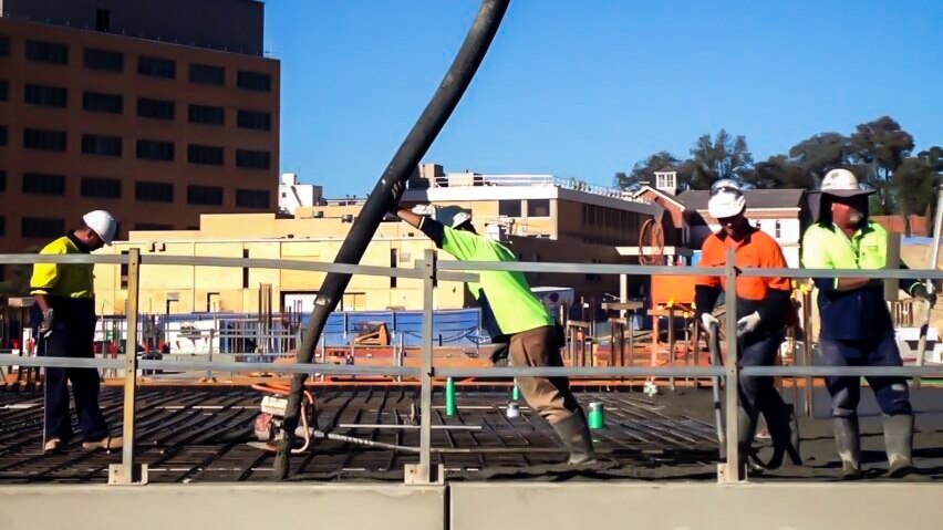 Workers pour concrete for what will become the first floor at the Bendigo hospital build site