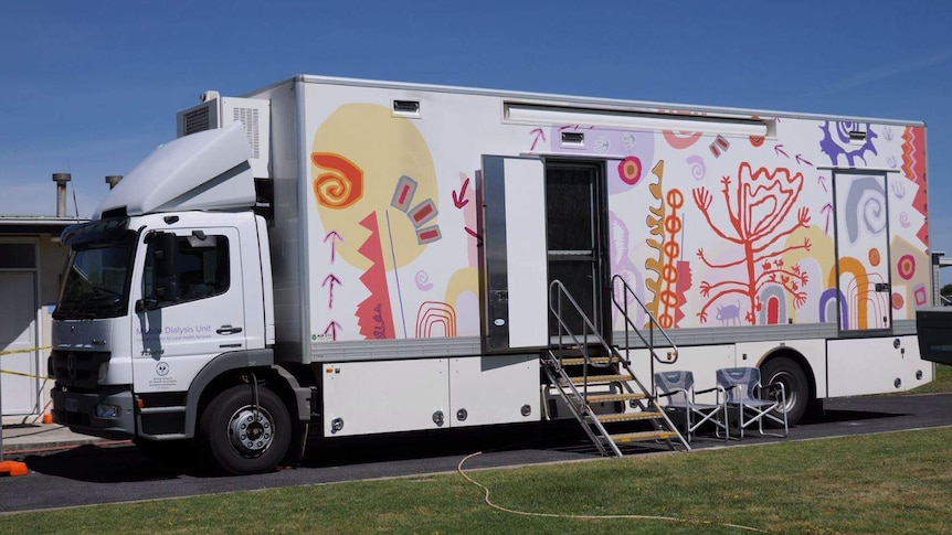 A brightly patterned bus with steps up to the carriage, the front of the bus says "Mobile Dialysis Unit"