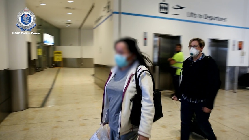 A woman escorted by police at an airport.