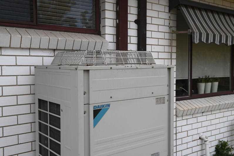 An air conditioning unit on the outside of a brick house.