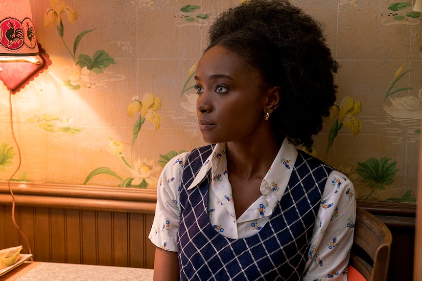 Close-up colour still of KiKi Layne sitting near lamp and against wallpapered wall in 2018 film If Beale Street Could Talk.