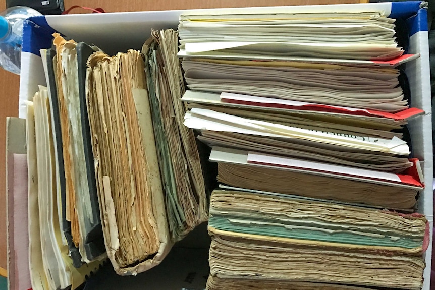 Old, deteriorating, books standing in a cardboard box.