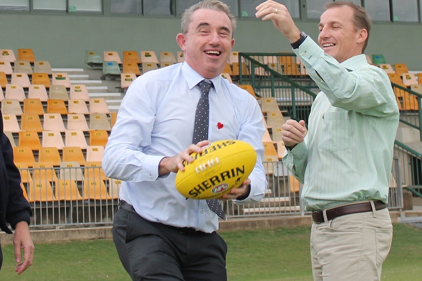 Page MP Kevin-Hogan catches a football at Lismore's Oakes Oval in 2018 with then mayor Isaac Smith.