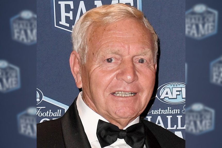 A head and shoulders shot of Barry Cable in a tuxedo smiling for a photo in front of a blue backdrop.
