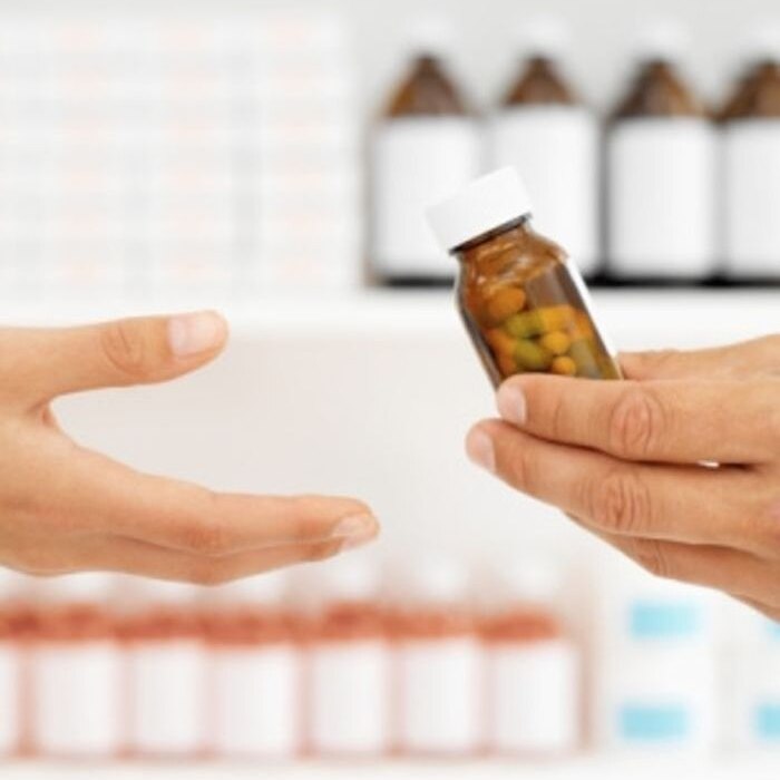 Pharmacist handing bottle of pills to patient.