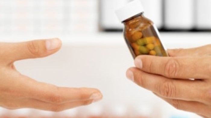 Pharmacist handing bottle of pills to patient.