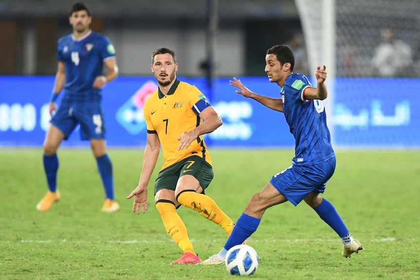 Mat Leckie passes the ball past a Kuwait player