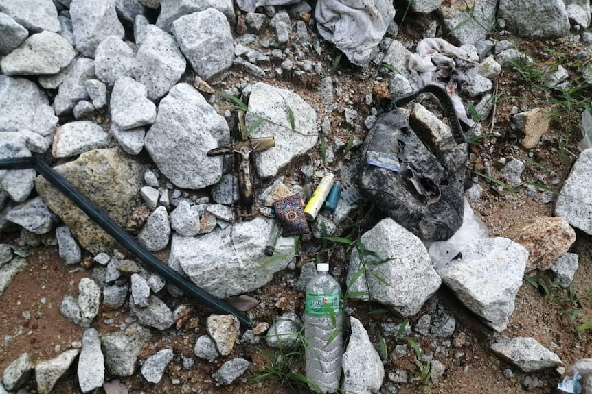 Personal belongings lying on a pike of rocks.