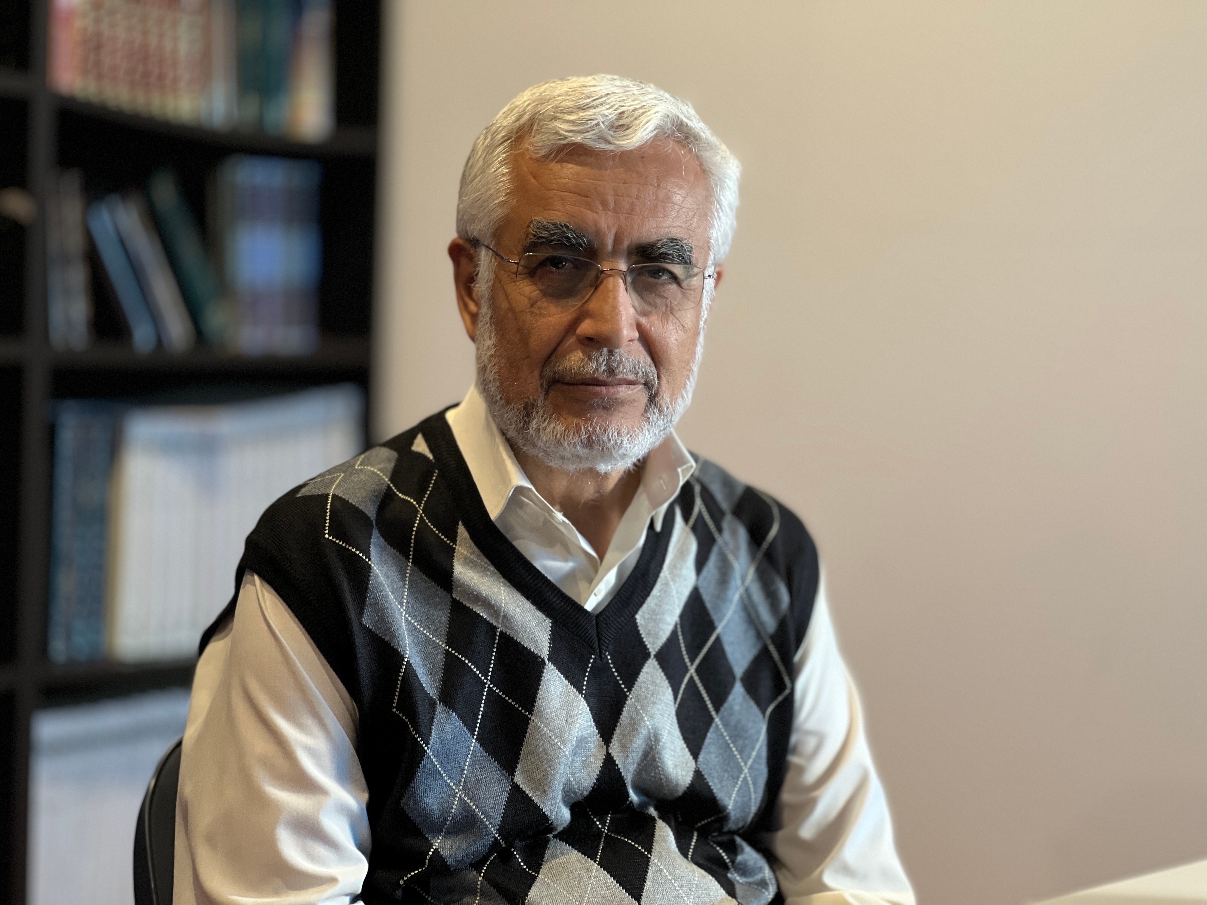 A man in a vest with white hair and glasses 