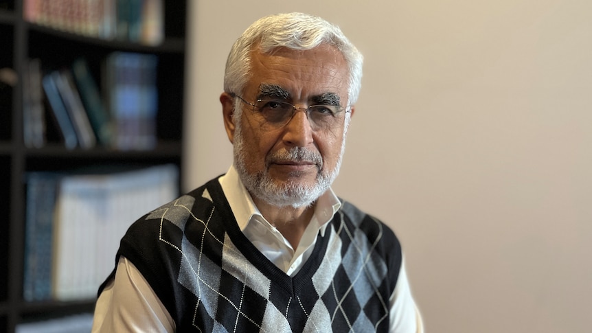 A man in a vest with white hair and glasses 