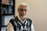 A man in a vest with white hair and glasses 
