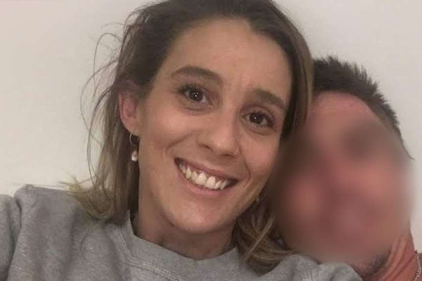 A selfie of Danielle Easey, a man is next to her but his face is blurred. 