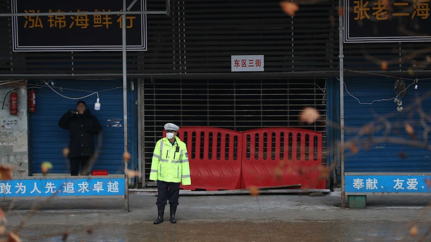 A police officer wearing a mask stands in front of the closed seafood market in Wuhan.