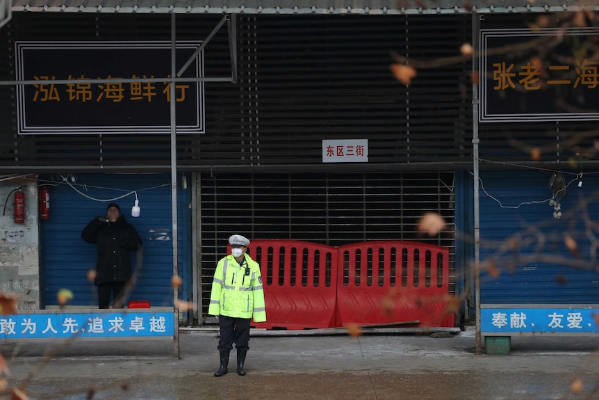 A police officer wearing a mask stands in front of the closed seafood market in Wuhan.