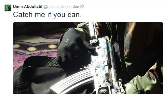 The tweet shows someone holding a large machine gun and wearing a camouflage jacket.