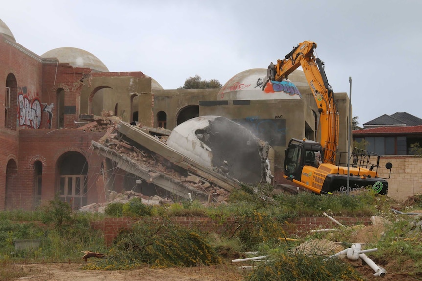 A large yellow digger works on demolishing the Taj on Swan.