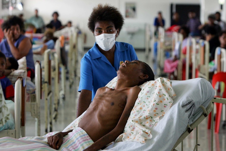 A nurse helps move a patient dying of HIV-AIDS in Port Moresby
