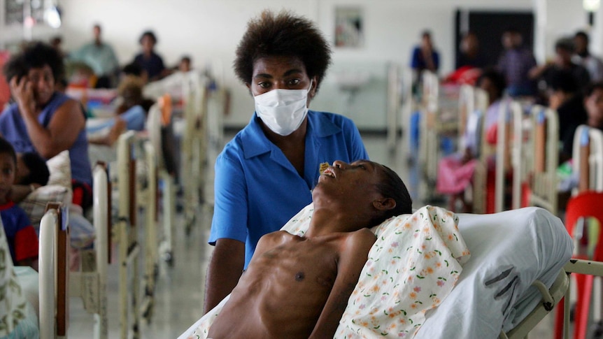 A nurse helps move a patient dying of HIV-AIDS in Port Moresby.