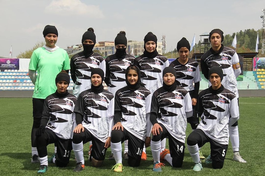 a group of women including Adiba Ganji in a soccer team photo on a soccer pitch