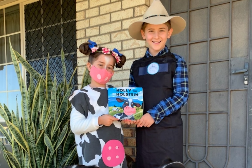 Young girl dressed as a dairy cow and boy dressed as a famer holding book. 