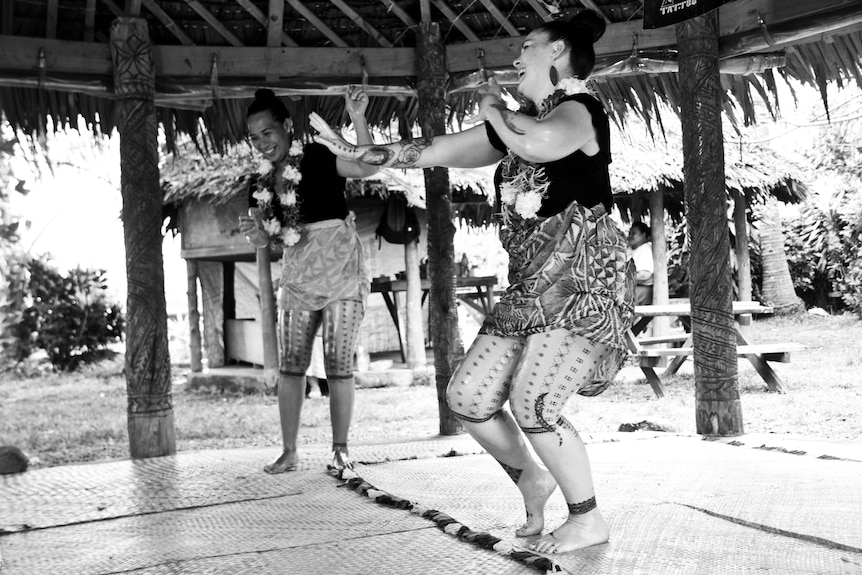 Black and white image of two women performing siva samoa after receiving their malu.