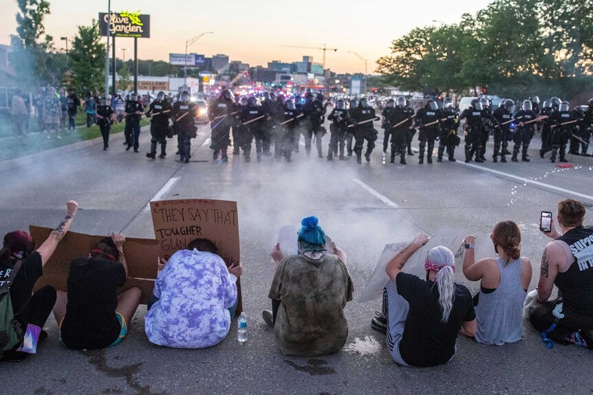 Omaha police fire tear gas as they approach protesters sitting on the road.