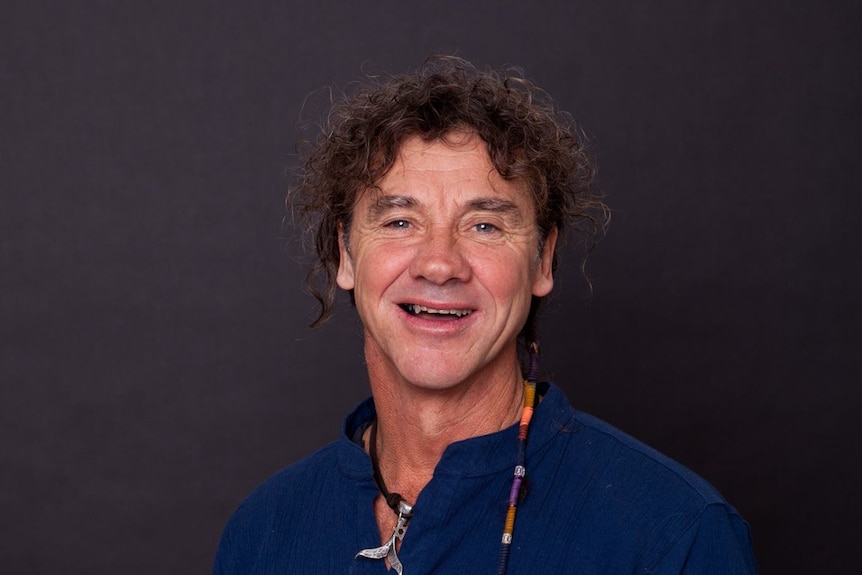 A middle-aged man with curly hair smiling for a profile shot