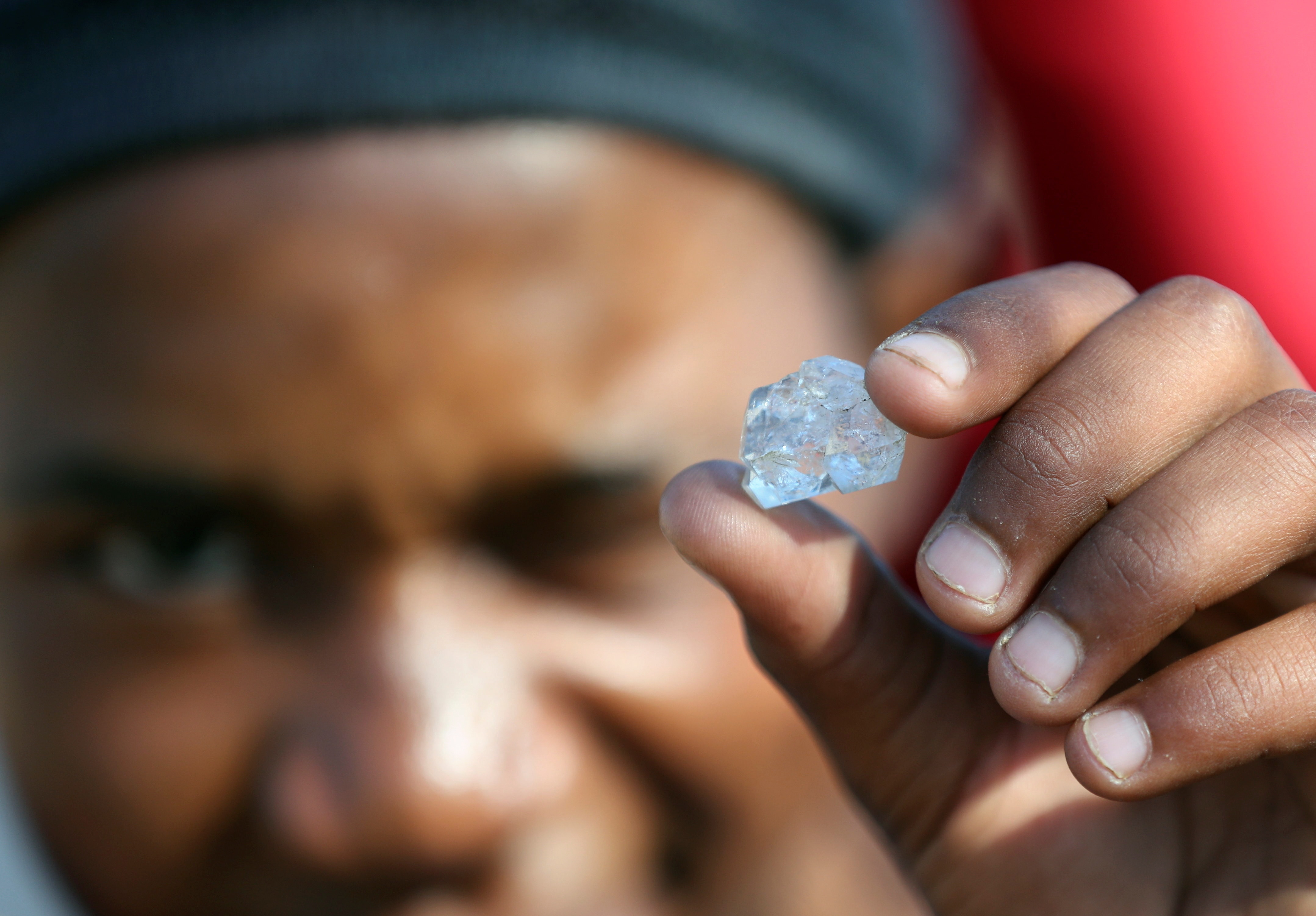 A man holds a clear crystal up to the camera in KwaHlathi following a reported diamond rush