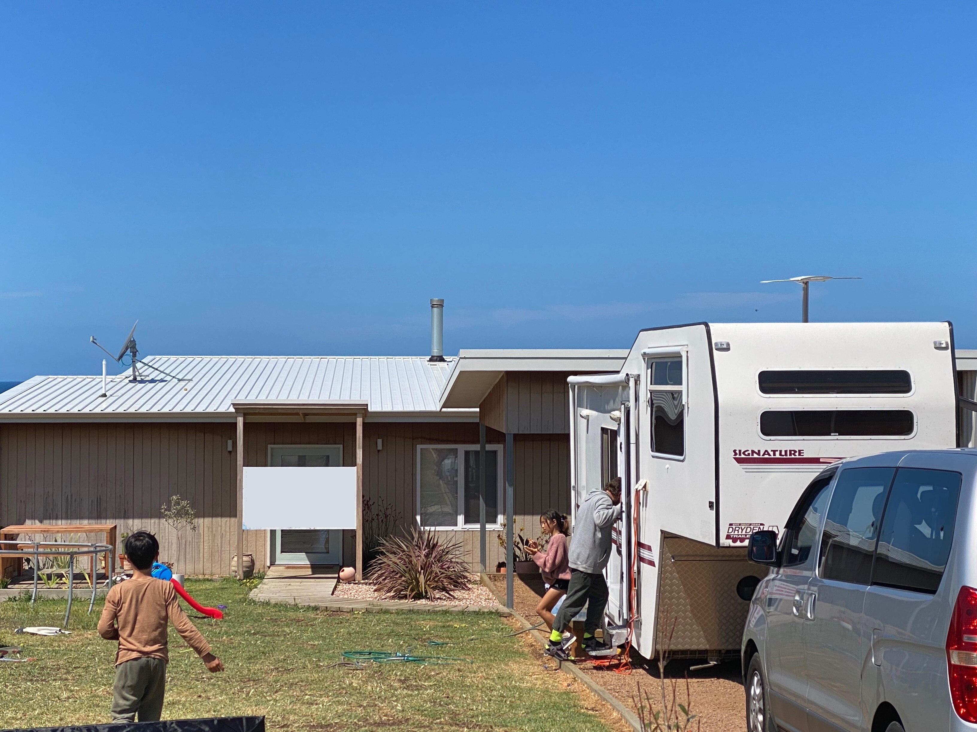 A home with a caravan in the driveway and a young boy in the front yard.