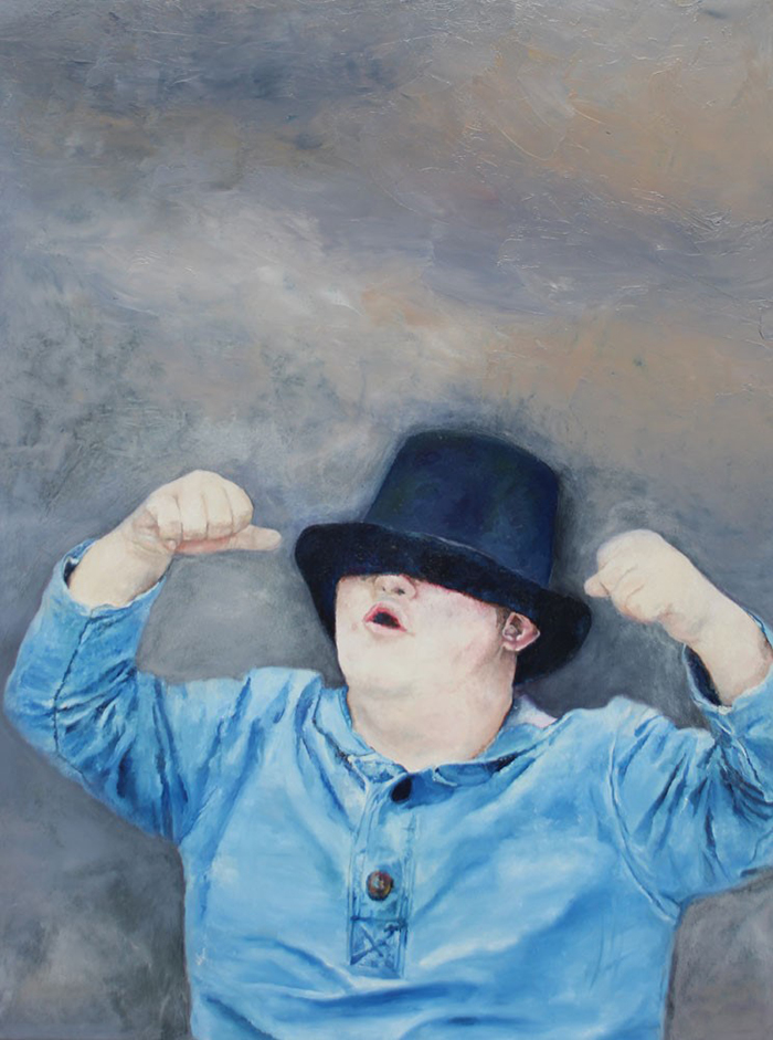 A portrait of a boy with Down Syndrome wearing a black hat covering his eyes and holding his fists in the air.