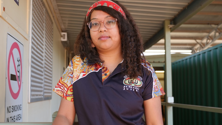 a woman looks into a camera standing on a walk way