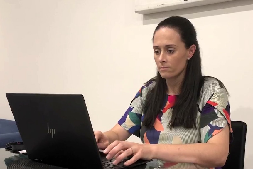 Dr Jaclyn Brown sitting at a table typing on a laptop computer