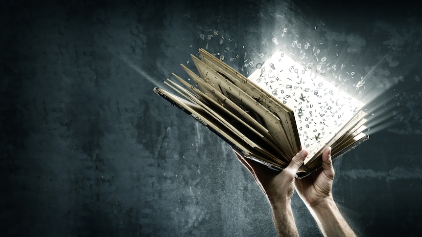 Two hands holding a glowing book. Letters are flying off the pages and floating around.