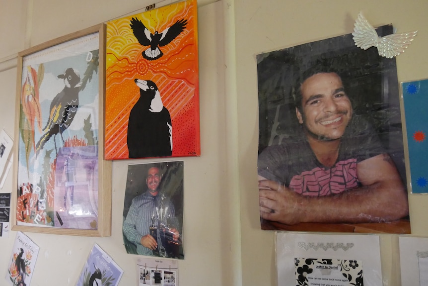 A wall with pictures of a man and some painted magpies. 