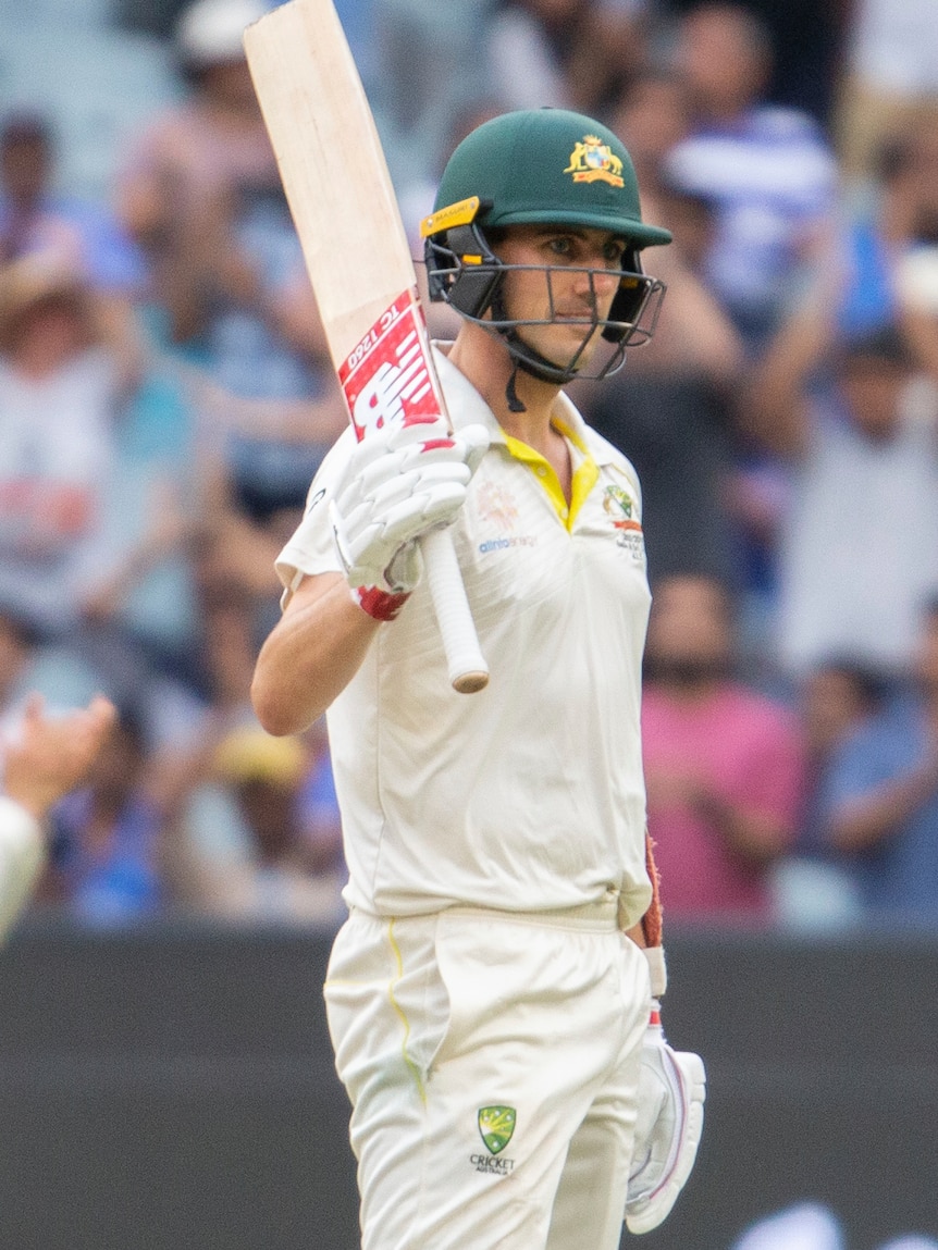 Pat Cummins raises his bat after reaching a half-century against India at the MCG