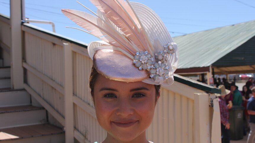 A rose gold headpiece with silver gems and light pink feathers