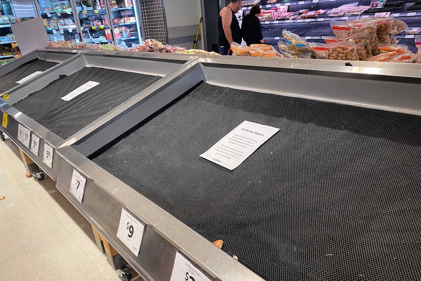 Empty shelves in a supermarket vegetable section.