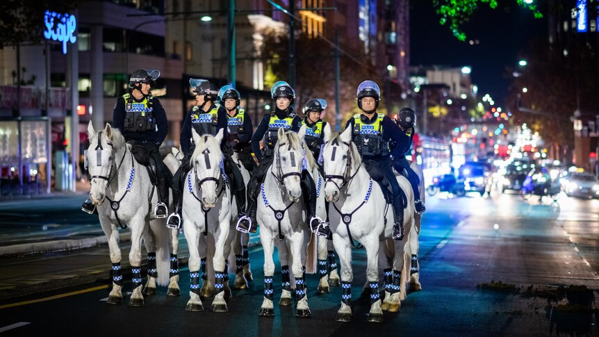 Police officers on police horses on a street at night