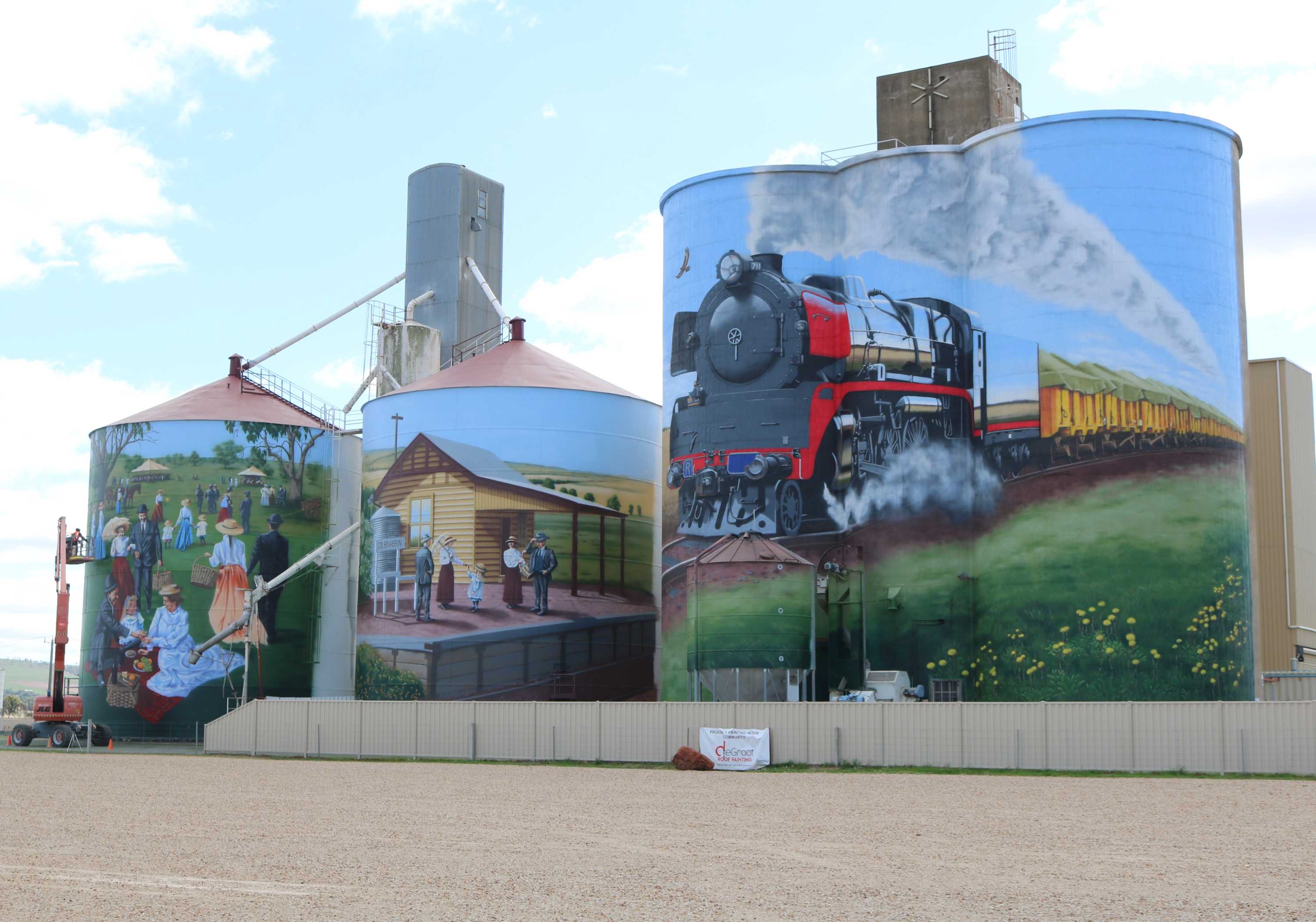 three silos with picture of train, train station and picnic painted on