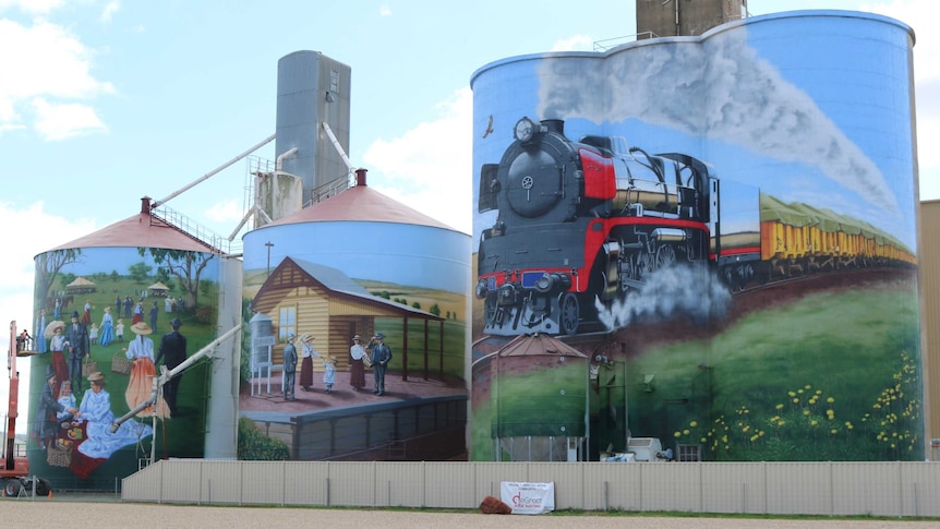 three silos with picture of train, train station and picnic painted on