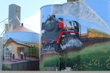 three silos with picture of train, train station and picnic painted on