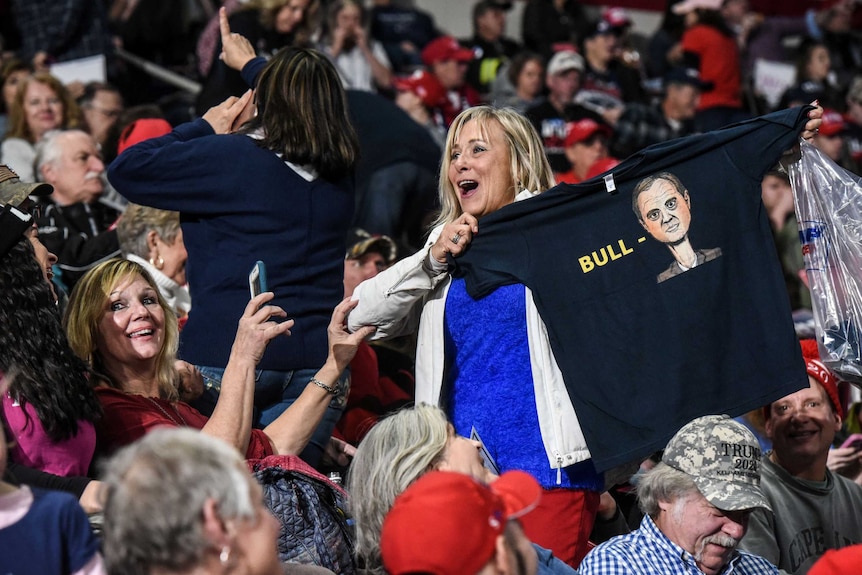 A woman holds up a t-shirt with the word "bull" written next to Schiff's head