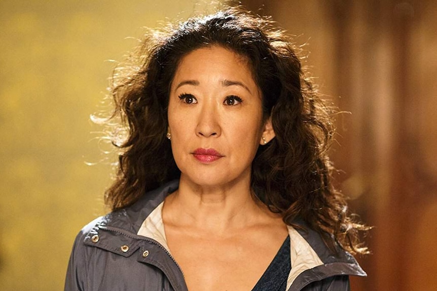 Sandra Oh, wearing a rain jacket, stares blankly ahead.