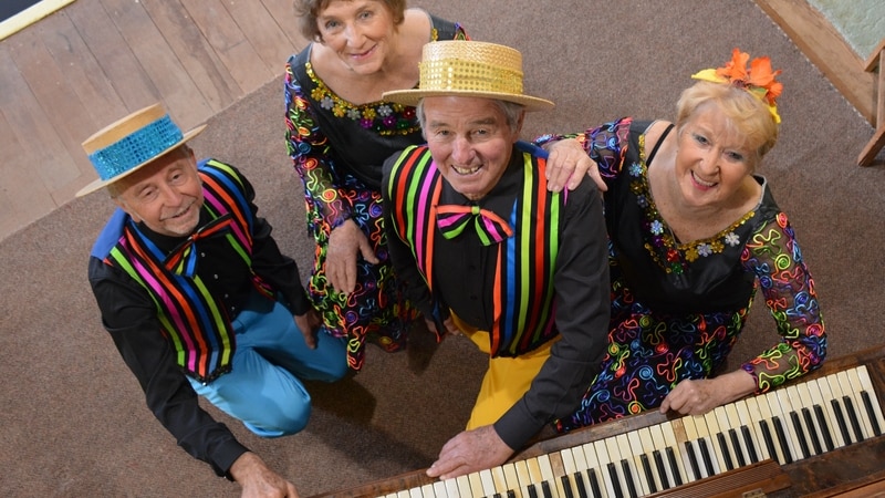 Four people in costume with a piano.
