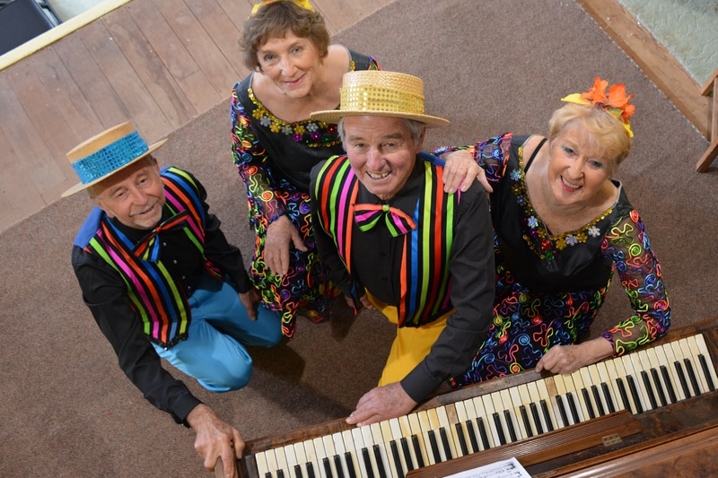 Four people in costume with a piano.