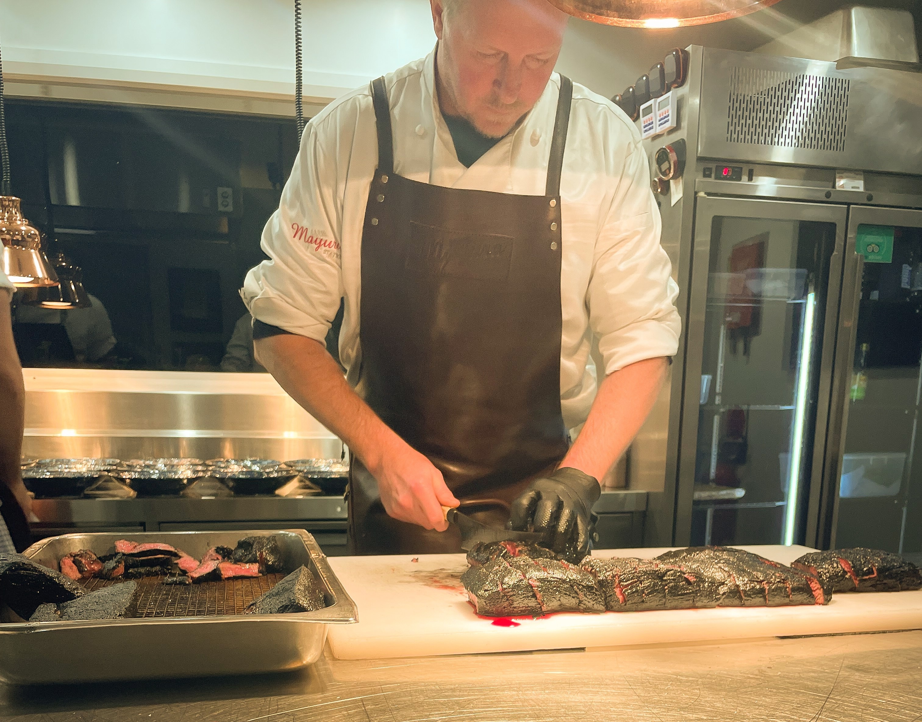 golf a chef carves meat on a stainless steel bench