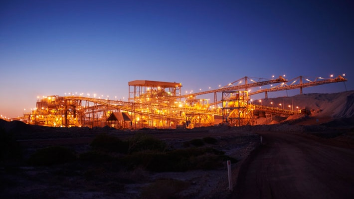 Night shot of the processing plant at Telfer gold mine, lit up against a deep blue sky.