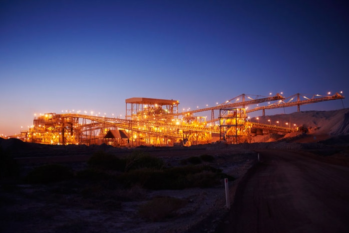 Night shot of the processing plant at Telfer gold mine, lit up against a deep blue sky.